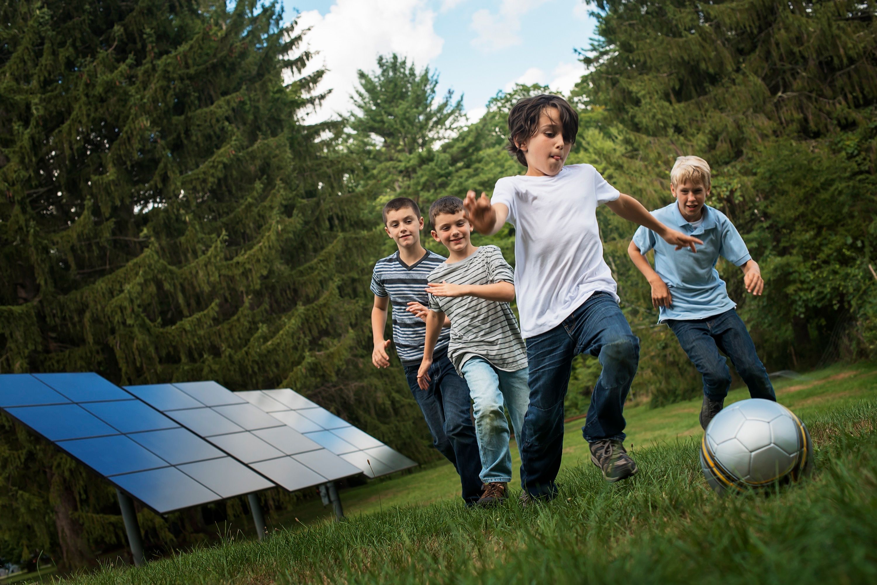 Jungs spielen Fussball vor Photovoltaik