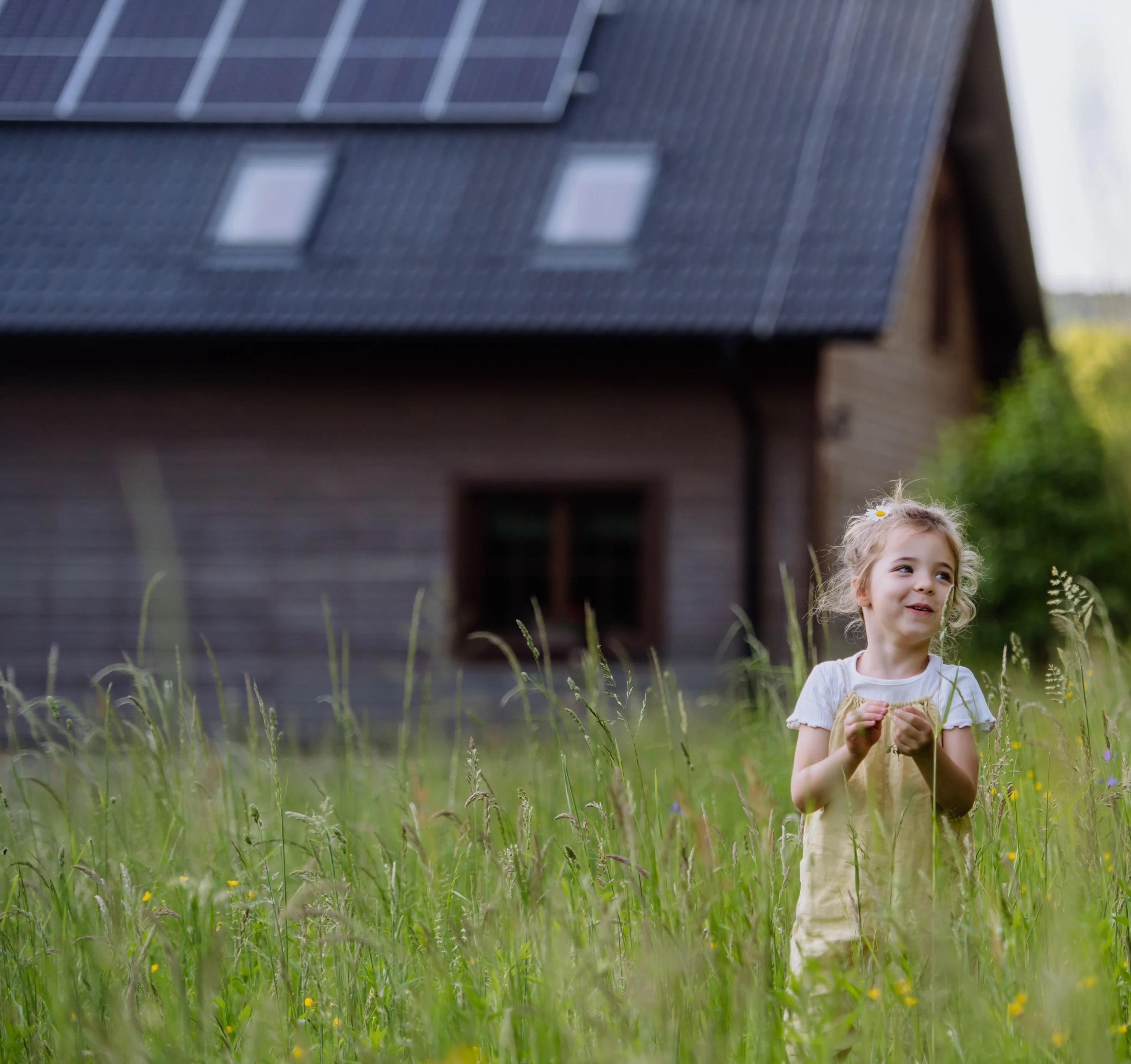 Kind vor Haus mit Photovoltaik-Anlage